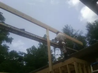 Carpenter setting a ridge beam over a new addition frame — Ice Dam Removal by Roofing Brothers in Grantville