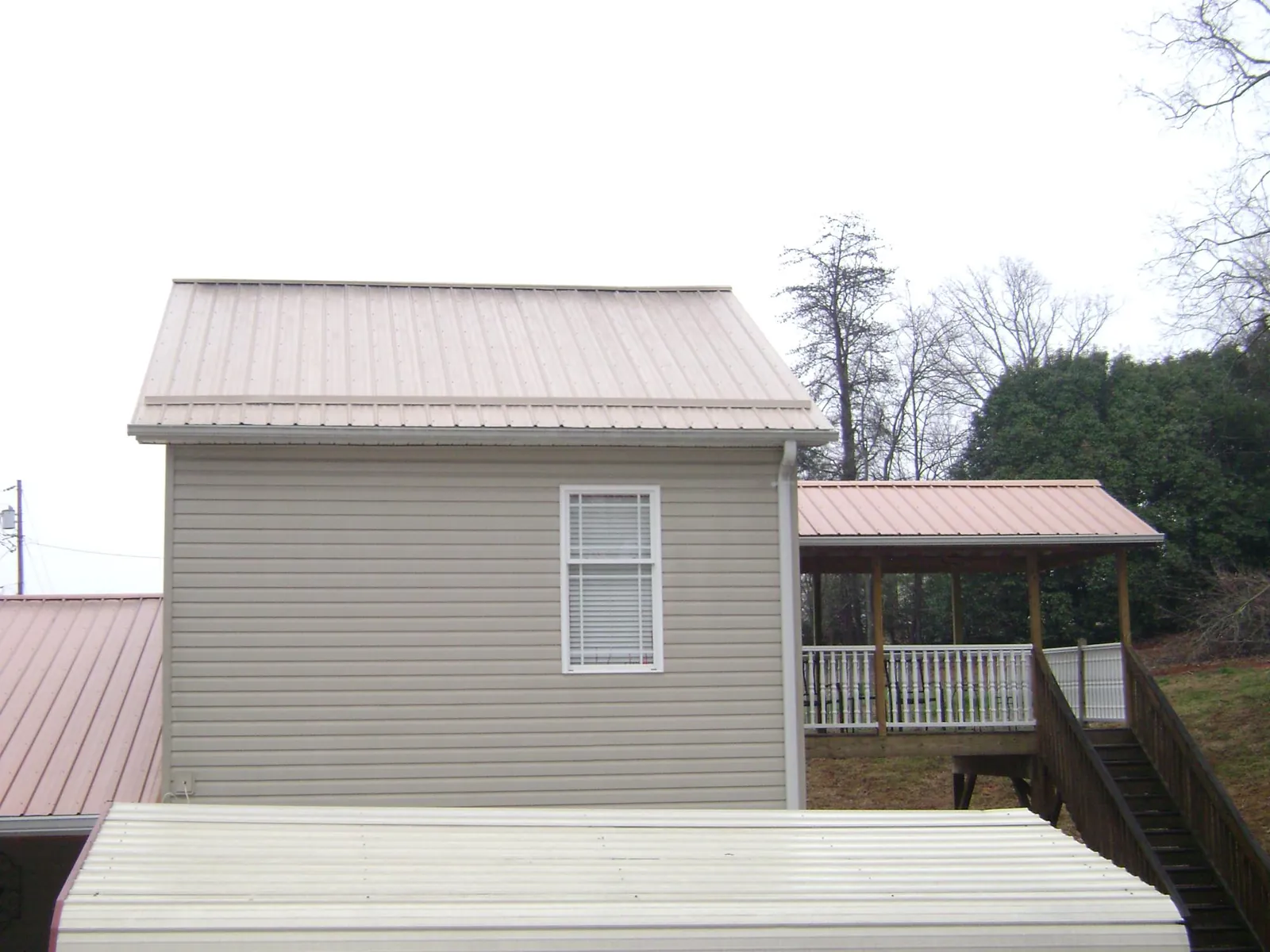 Tan metal roofs on a two story addition and attached porch, from a Roof Replacement job in Grantville